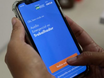 Imagem de um celular mostrando o aplicativo Auxílio Emergencial, que visa ajudar a população contornar os efeitos econômicos da pandemia de coronavírus